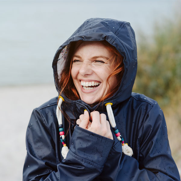 woman in rain coat laughing on the beach